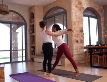 Yoga instructor guiding a student through a pose in a private class